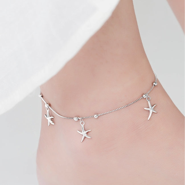 Silver anklet with starfish charms on a mannequin foot against a white background
