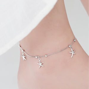 Silver anklet with starfish charms on a mannequin foot against a white background